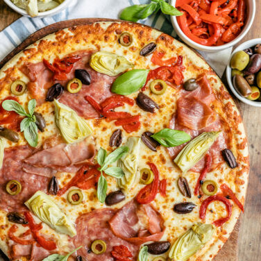 pizza topped with charcuterie board ingredients to resemble a snacking board