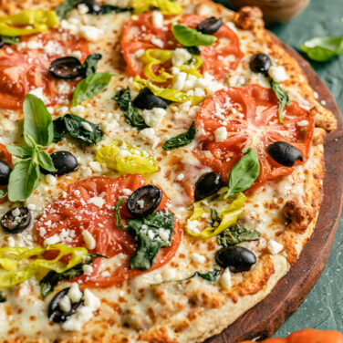 Pizza topped with olives, peppers, tomatoes and more