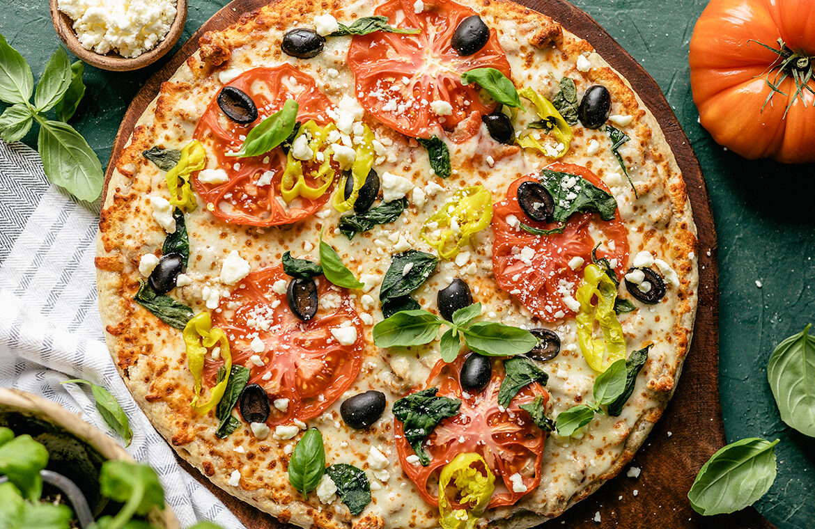 Pizza topped with olives, peppers, tomatoes and more
