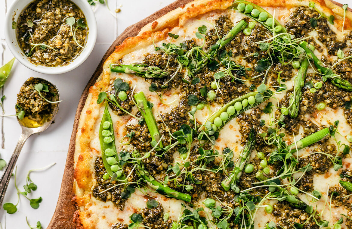 Pizza topped with peas, pesto, asparagus, and micro greens