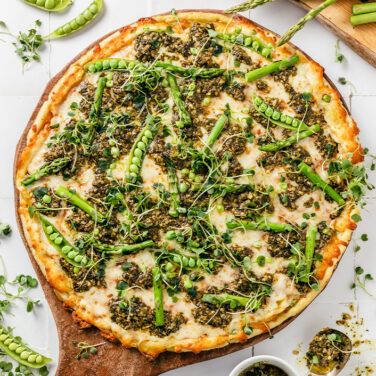 Pizza topped with peas, pesto, asparagus, and micro greens