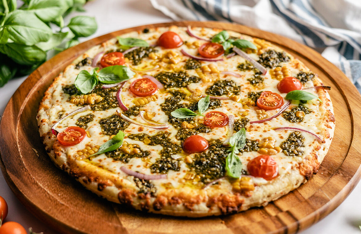 grilled pizza topped with tomatoes, pesto, onion, and more