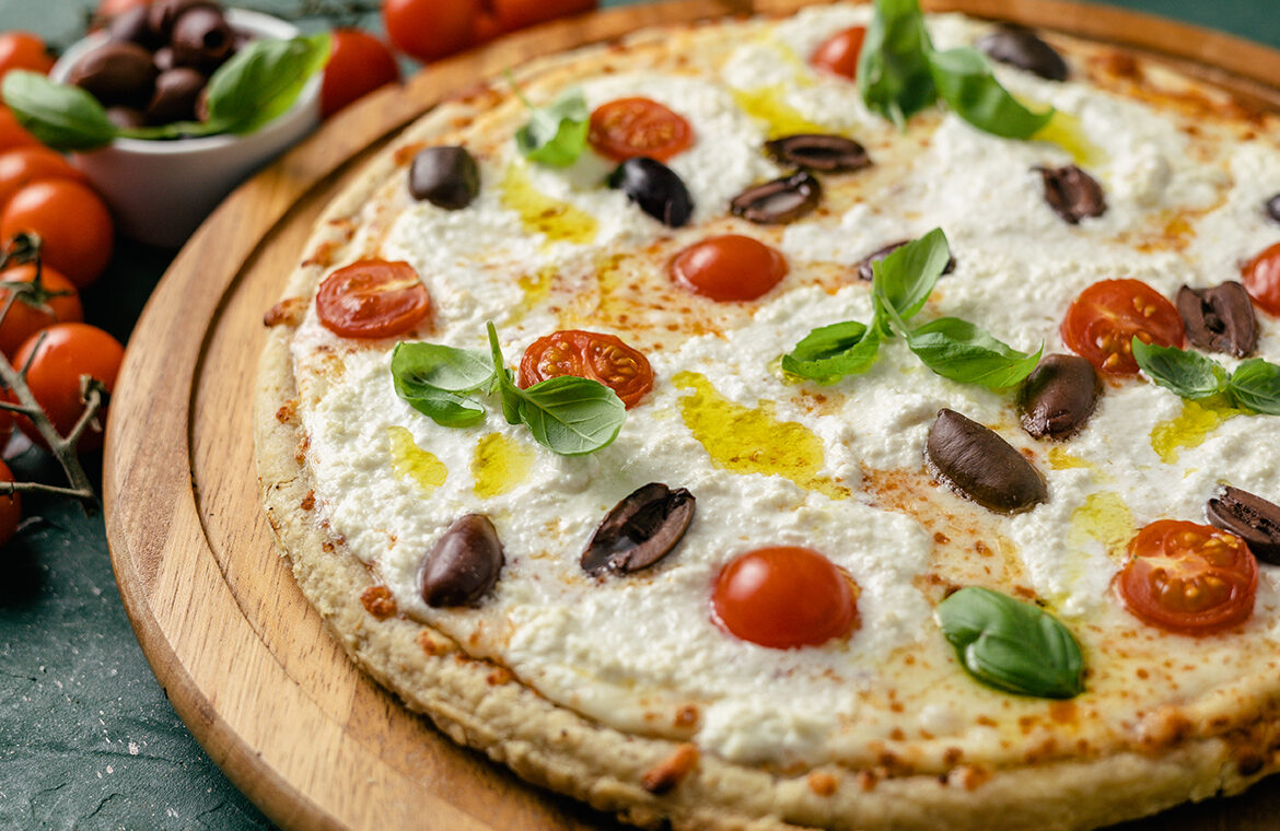 pizza topped with olives, tomatoes, olive oil, basil, and more