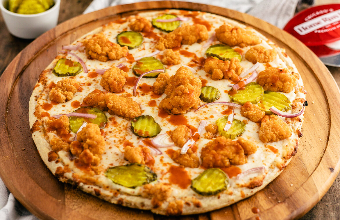 pizza topped with popcorn chicken, buffalo sauce, and pickles