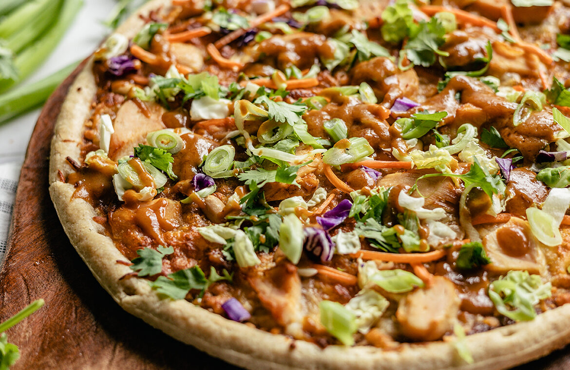 Pizza crust topped with cabbage, chicken, peanuts, cilantro, and more