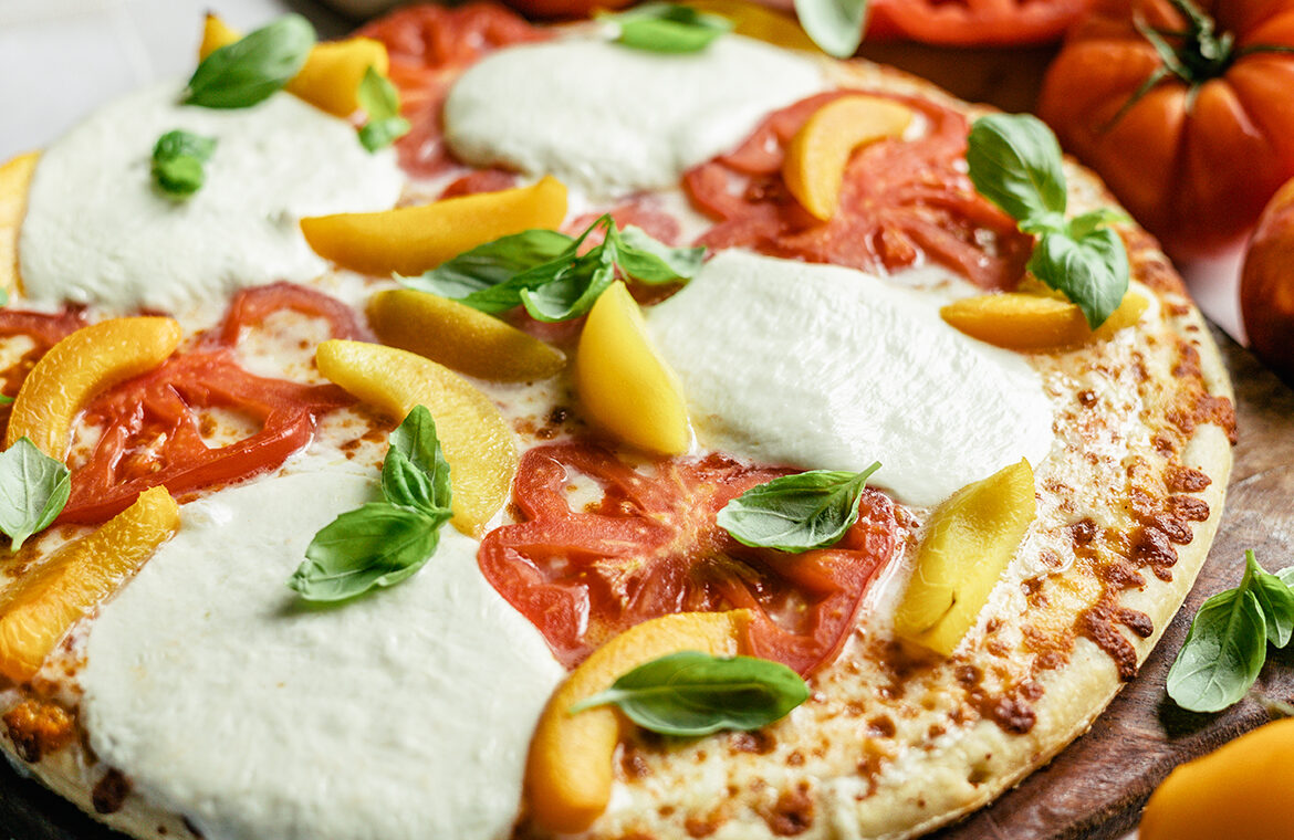 Pizza topped with tomato, peaches, and burrata cheese