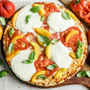 Pizza topped with tomato, peaches, and burrata cheese