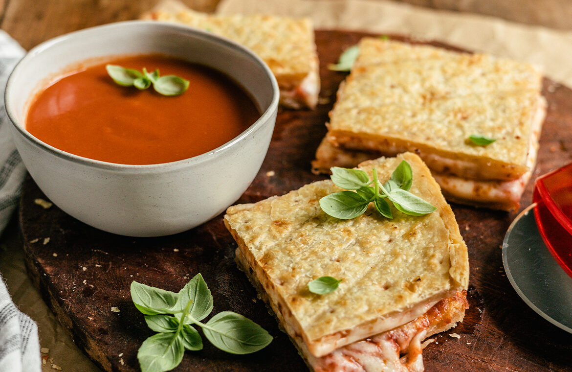 Pizza folded cheese side in to form a grilled cheese sandwich, being dipped into tomato soup