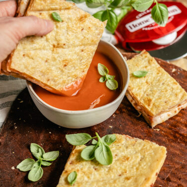 Pizza folded cheese side in to form a grilled cheese sandwich, being dipped into tomato soup