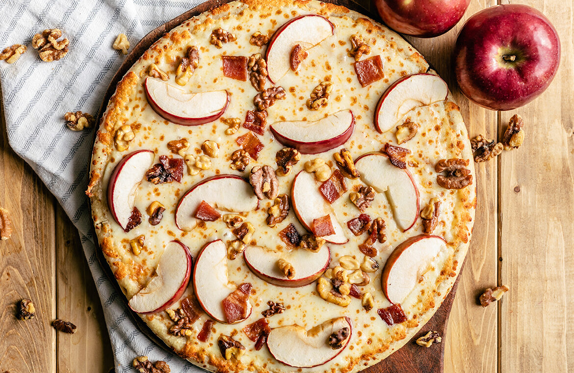 Pizza topped with apple slices, bacon, and walnuts