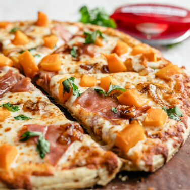 Pizza topped with squash, prosciutto and onion