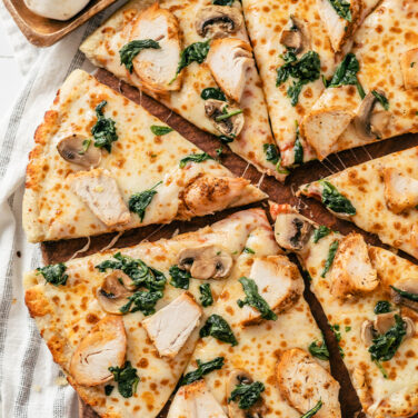 Pie cut pizza topped with turkey, spinach, and mushroom