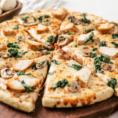 Pie cut pizza topped with turkey, spinach, and mushroom