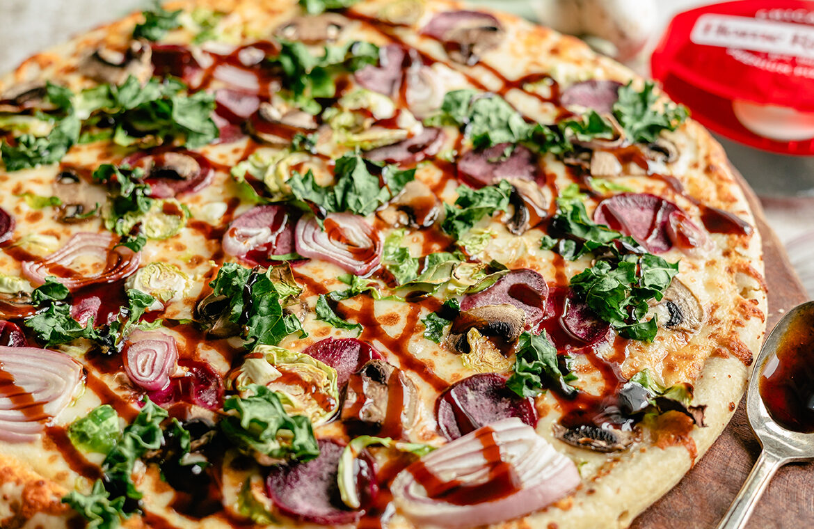 Pizza topped with brussels, kales, and balsamic drizzle
