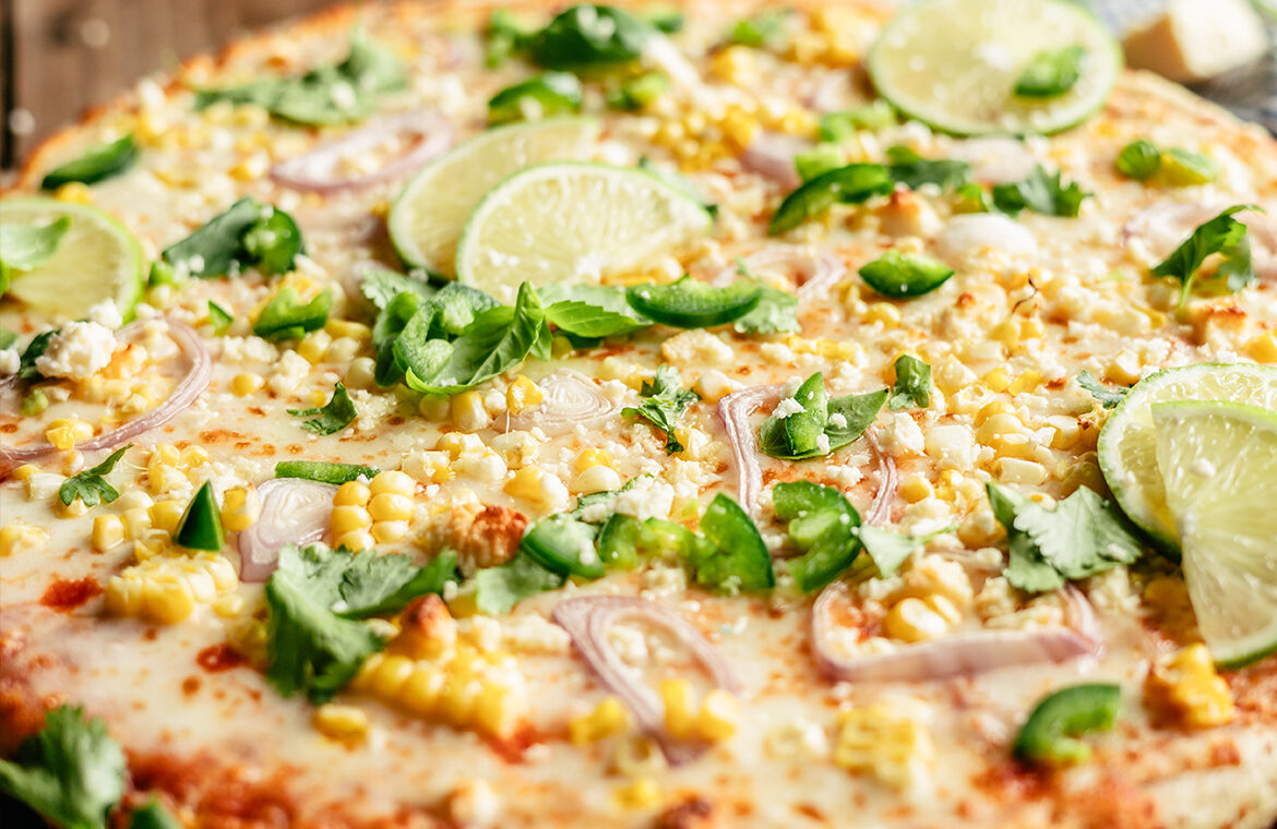 Pizza topped with corn, limes, cilantro, and more