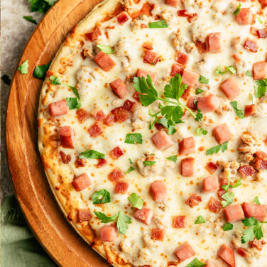 Pizza topped with ham, bacon, and more