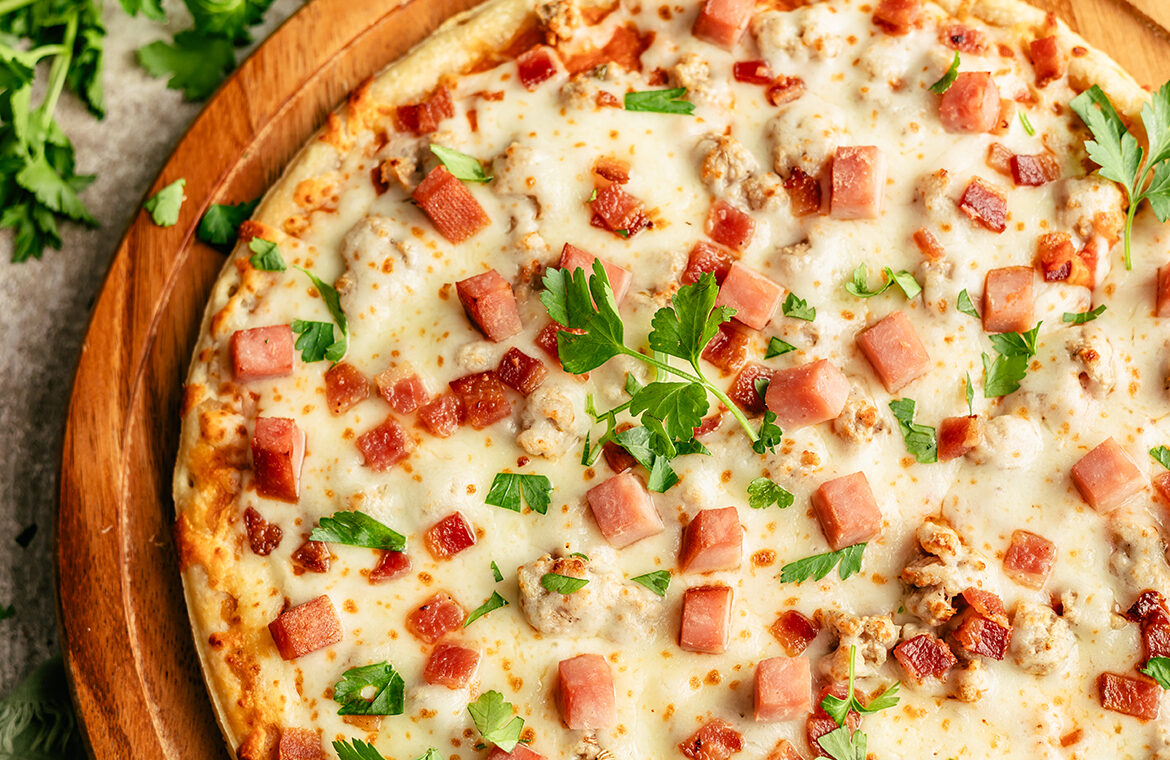 Pizza topped with ham, bacon, and more