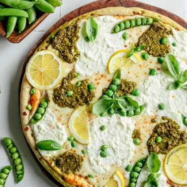 Pizza topped with lemon slices, ricotta and snap peas