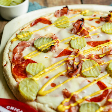 Pizza topped with ham, swiss, pickles, and mustard drizzle