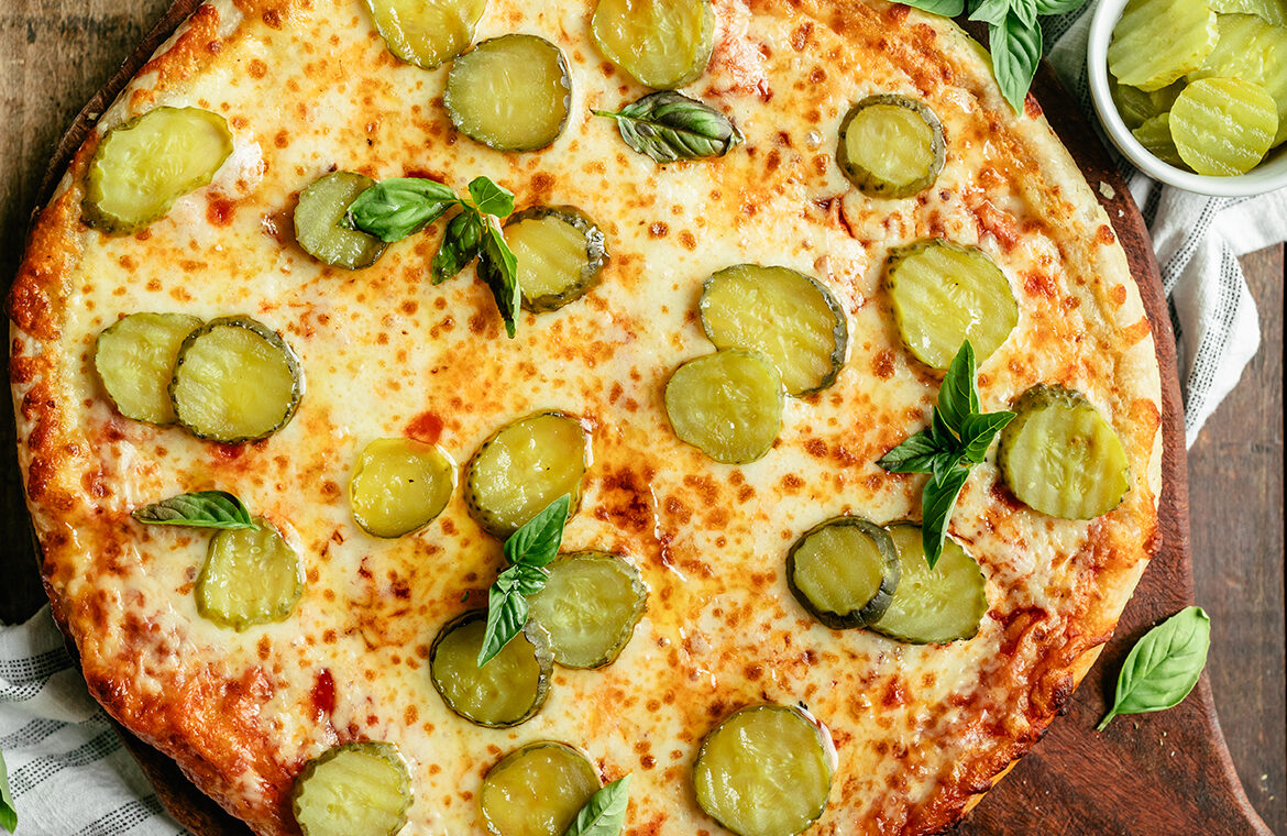 Baked cheese pizza topped with pickles, chili infused oil, and fresh basil