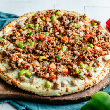 Baked pizza topped with ground beef, peppers, and tomatoes