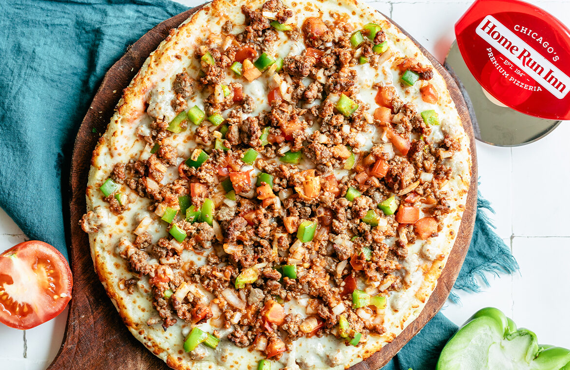Baked pizza topped with ground beef, peppers, and tomatoes