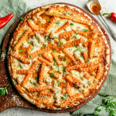 Baked pizza topped with crinkle cut sweet potato fries and chili infused oil