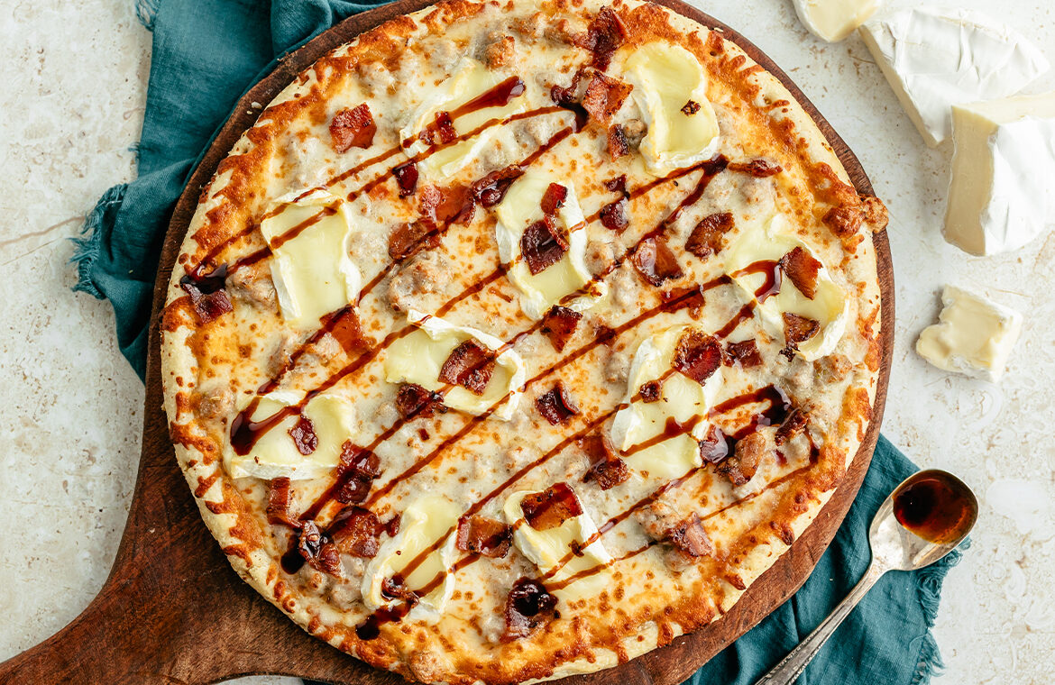 Baked pizza topped with Brie, Hot Honey, and bacon