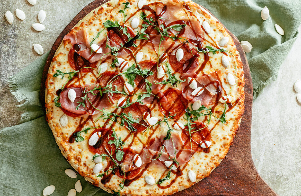 Baked Pepperoni Pizza topped with balsamic, kale, and prosciutto