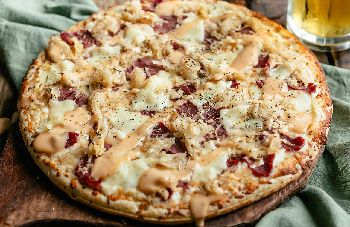 Baked pizza topped with reuben sandwich ingredients