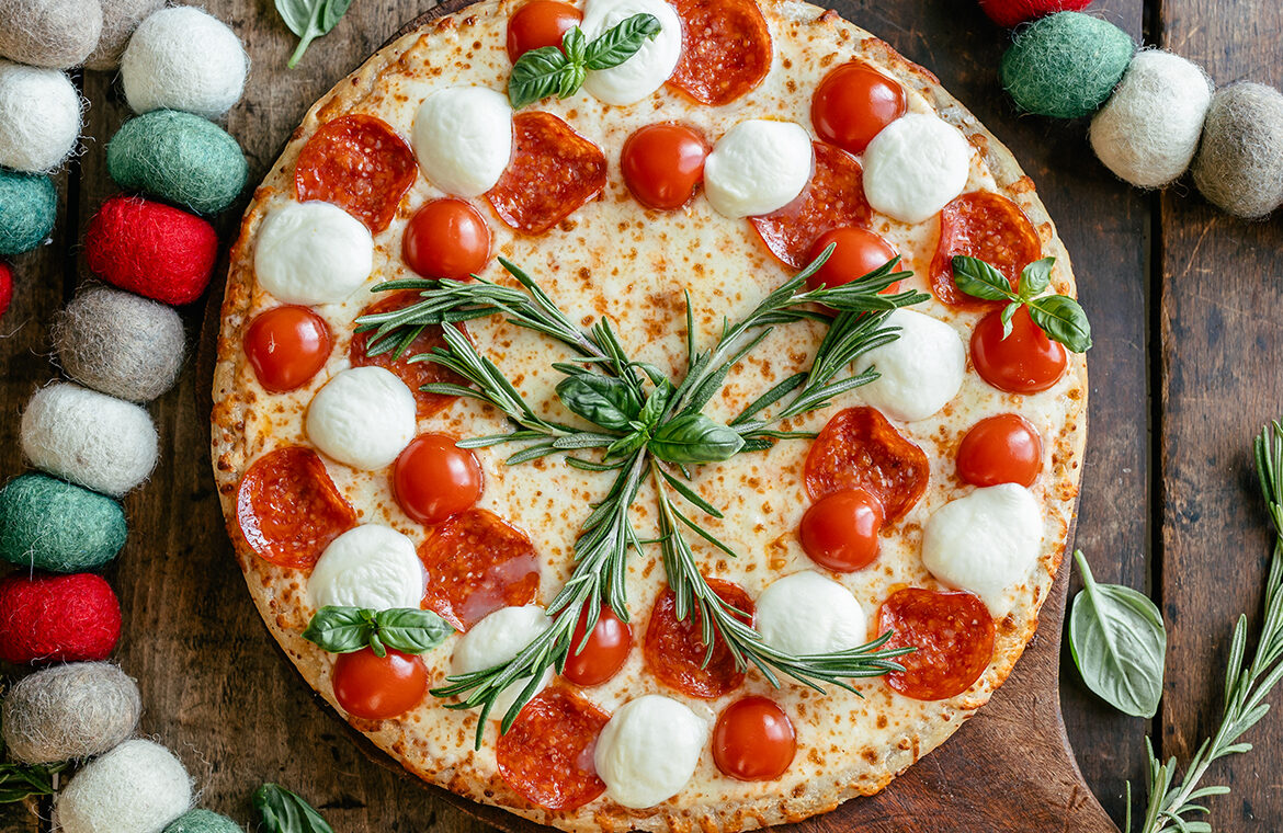Baked Pizza topped with pepperoni,, mozzarella balls, basil, and rosemary to resemble a holiday wreath