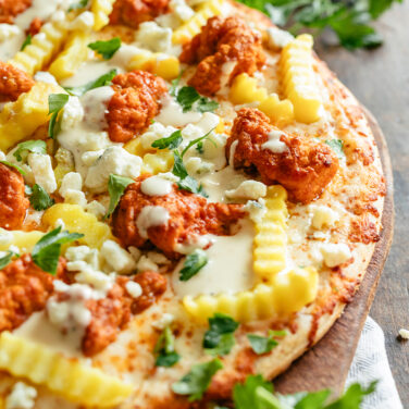 Baked pizza topped with recipes ingredients like fries and chicken wings