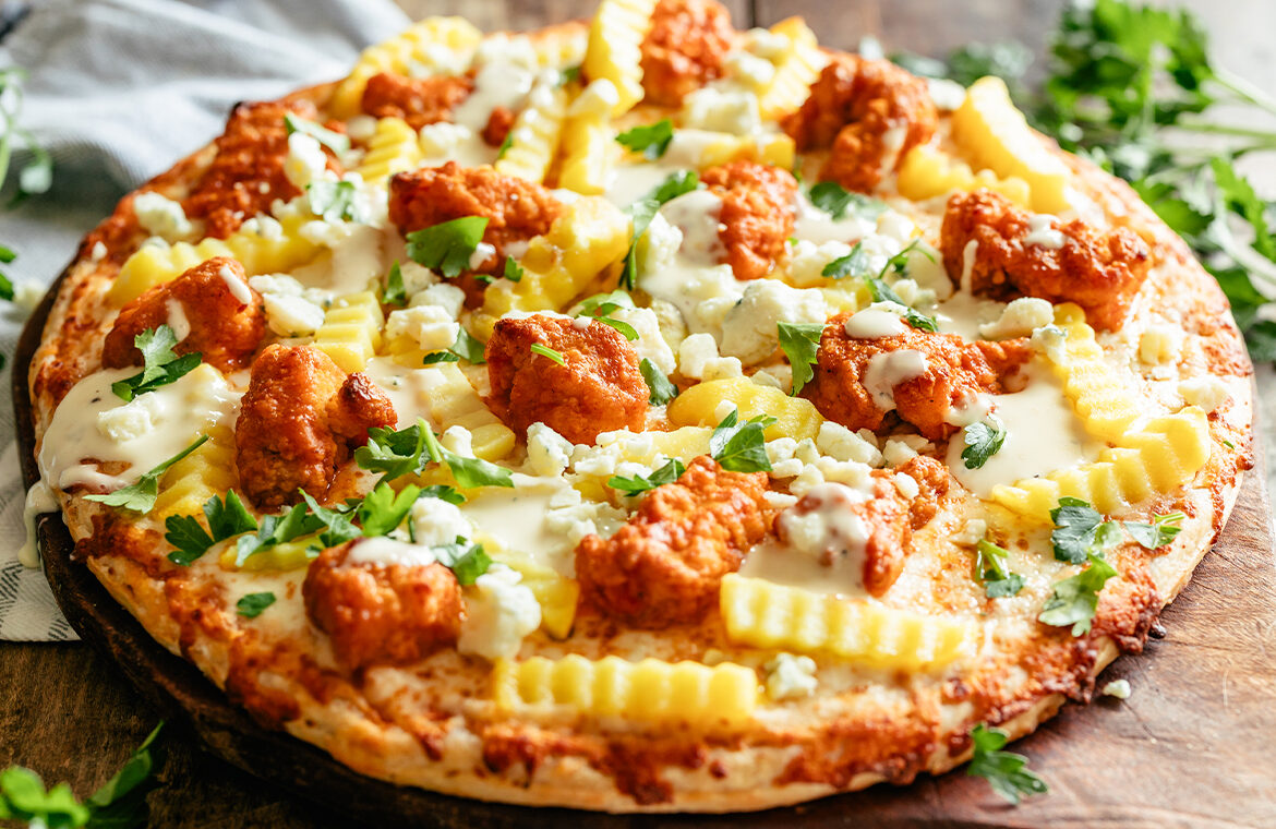 Baked pizza topped with recipes ingredients like fries and chicken wings