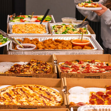 Various menu items laid out in a line for people to serve themselves