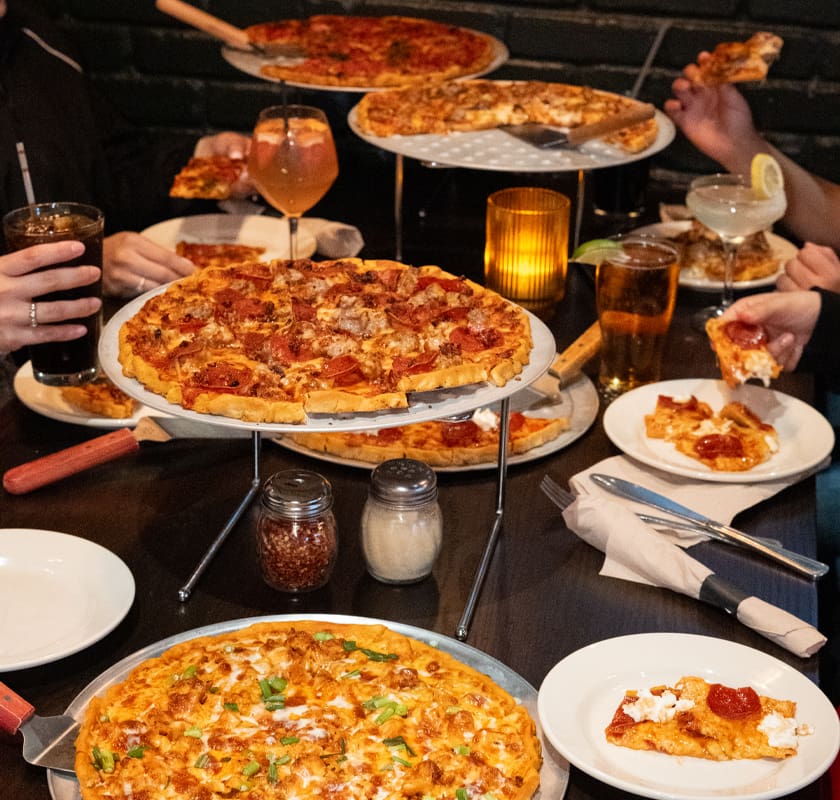 Restaurant pizza spread with hands grabbing pizza slices