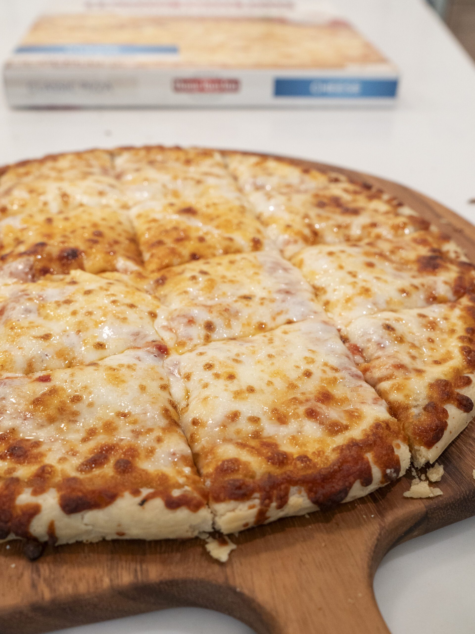 Home Run Inn classic thin crust cheese pizza cut into square slices with a frozen cheese pizza box in the background.
